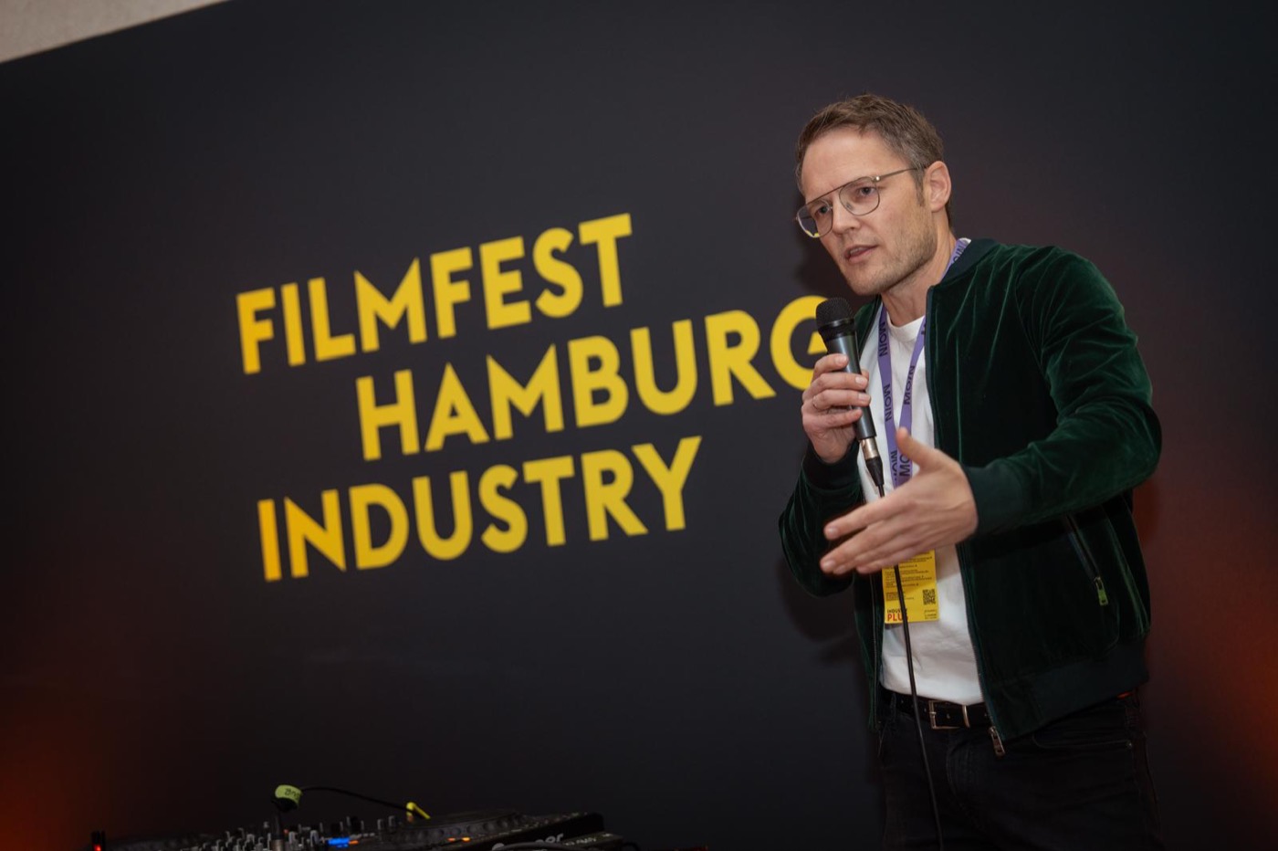 Person spricht mit Mikrofon vor dem Schriftzug Filmfest Hamburg Industry